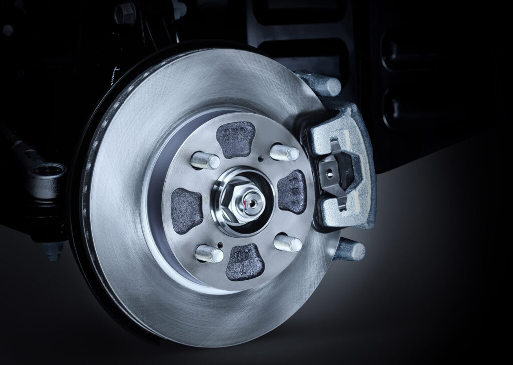 Brake calliper and pads mounted over a brake disc on a car wheel hub