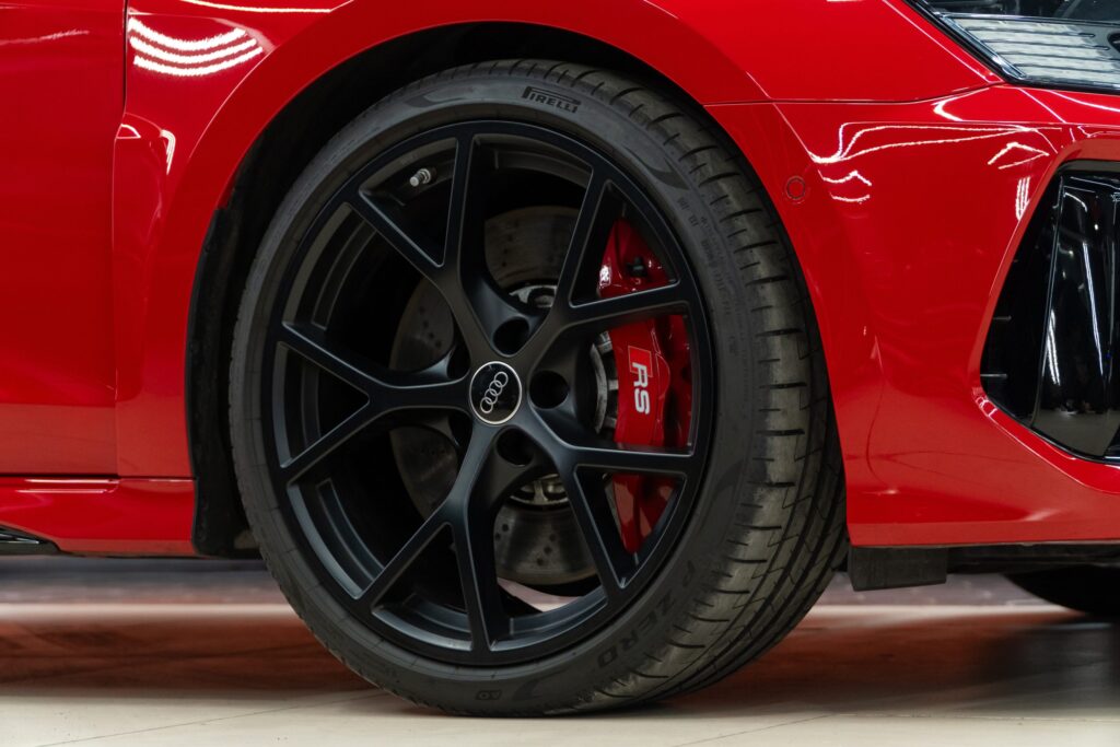Car wheel showing a large brake disc and red brake calliper behind the alloy wheel